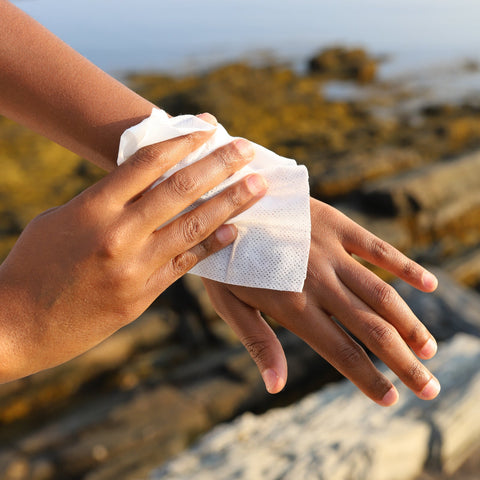 Person wiping their hands with herban essentials wipe