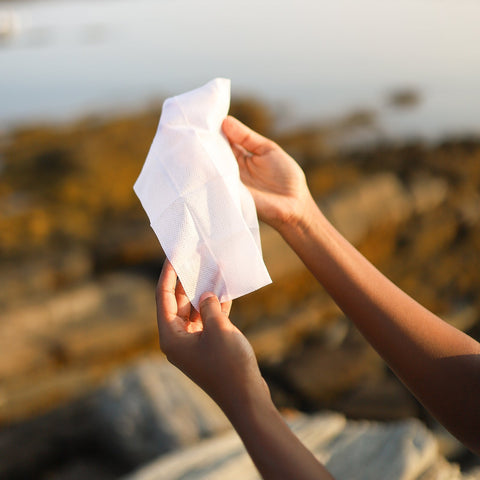 Person holding a ' Herban Essentials' eucalyptus wipe at beach