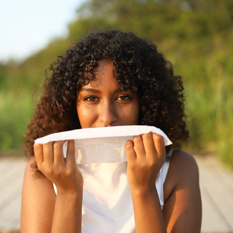 Woman holding a herban essentials wipe over her face to inhale the essential oil