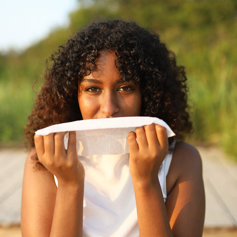 Woman holding a inhaling heban essentials orange essential oil towelette at the beach