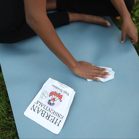 girl wiping her yoga mat with herban essentials lavender yoga towelette