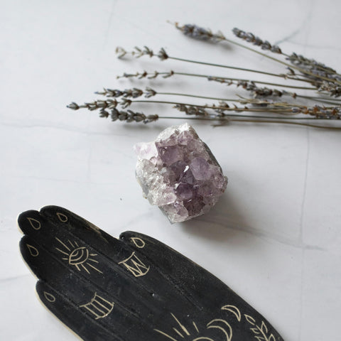 Amethyst crystal with dried lavender sprigs and a celestial hand-carved incense holder on white marble background, symbolizing a calming lavender ritual and aromatherapy for relaxation and sleep.