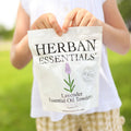 Child holding a bag of Herbal Essentials Lavender Essential Oil Towels in a grassy outdoor setting.