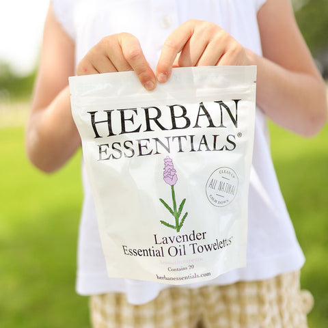 Child holding a bag of Herbal Essentials Lavender Essential Oil Towels in a grassy outdoor setting.