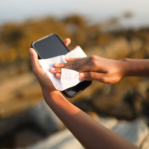 Person cleaning a smartphone with a lemon herban essentials essential oil wipe 