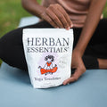 Person holding a Herban Essentials yoga towellettes package on yoga mat.