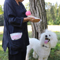 Person holding an essential oil dog towelette  with a white dog standing next to them outdoors.