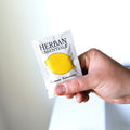 person holding herban essentials lemon essential oil towelette in bathroom