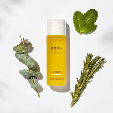 Espa bottle of Energising Bath & Body Oil with green leaves on a white background